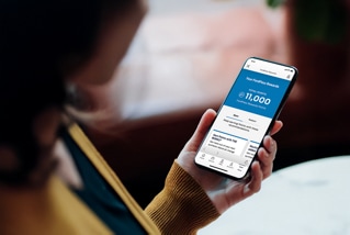 Person holding a smartphone displaying a screen in the FordPass app.
