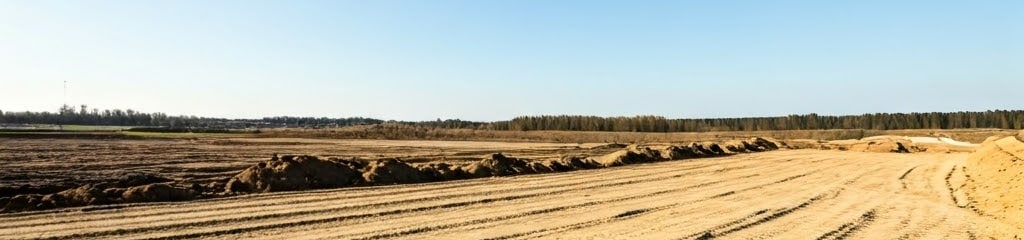 Dirt road with tire tracks under an open blue sky