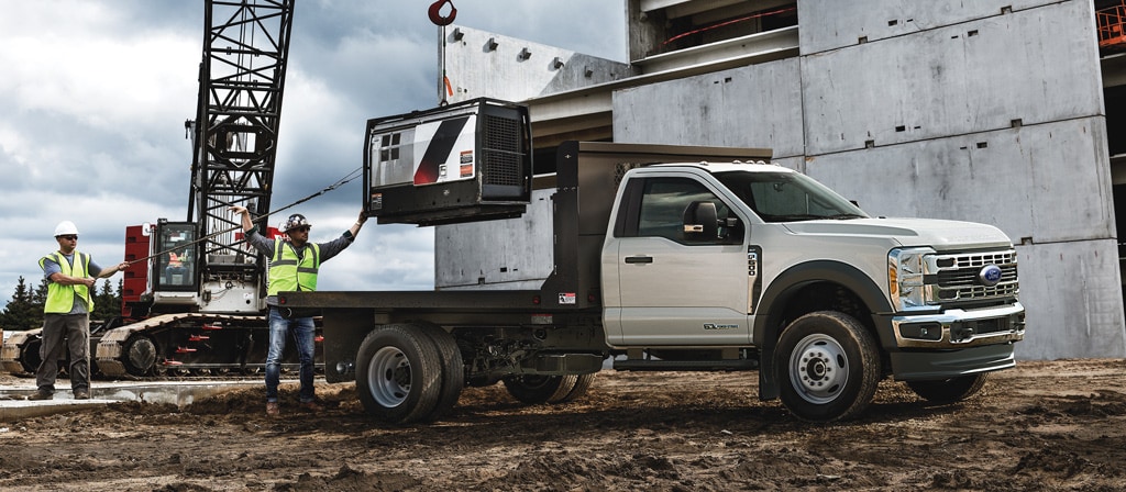 A 2026 Ford Super Duty® Chassis Cab parked on a construction site while something is being loaded onto the flatbed