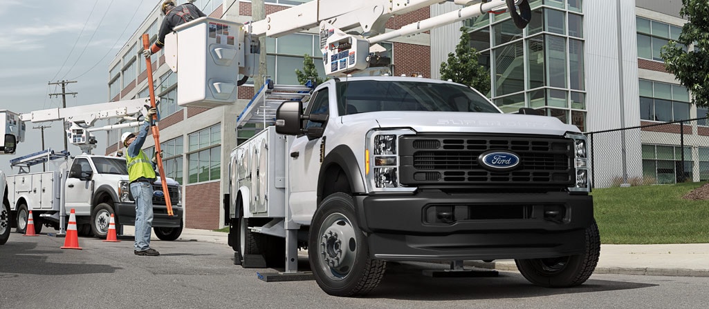 Two workers using the boom extension on a 2026 Ford Super Duty® Chassis Cab to fix an electric poll