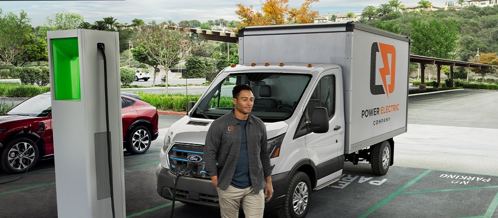 A white 2025 Ford E-Transit™ parked and charging at a public lot