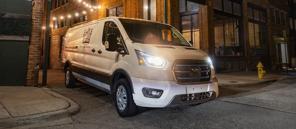 A white 2025 Ford E-Transit™ van backing into a delivery spot