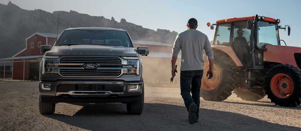 Person walking toward a 2025 Ford F-150 Platinum® pickup parked at a farm