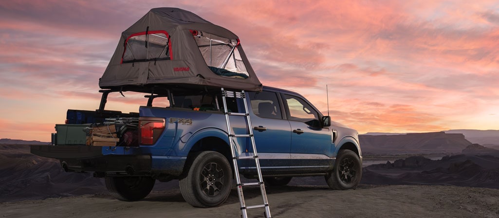 2025 Ford F-150® FX4® pickup in Atlas Blue with a Ford Accessories truck bed tent at dusk