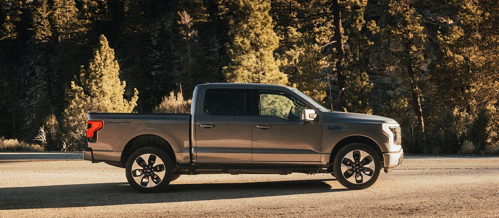 A 2025 Ford F-150® Lightning® side view is parked at sunset in a scenic location