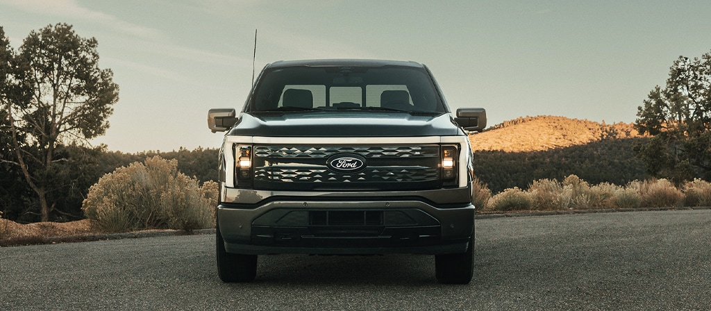 A 2025 Ford F-150® Lightning® is head on parked at sunset in a scenic location