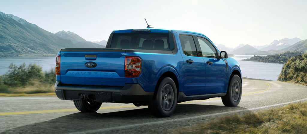 A 2025 Ford Maverick® pickup driving toward a mountain lake in the afternoon