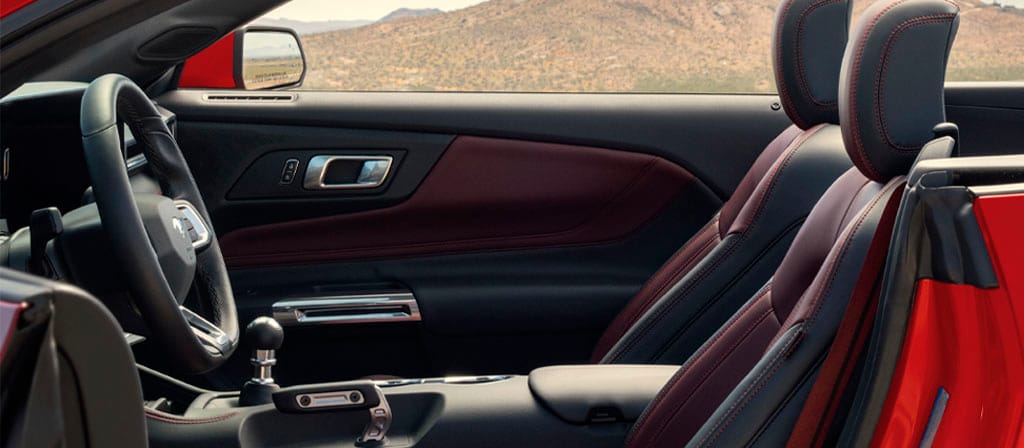Parked 2025 Ford Mustang® convertible with the driver's side door open showing the available Carmine Red interior