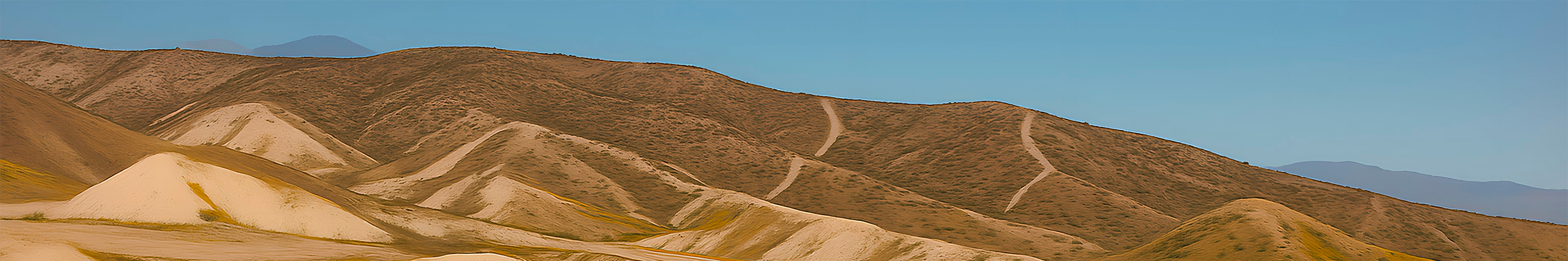 Panoramic view of desert hills with a light blue sky in the background