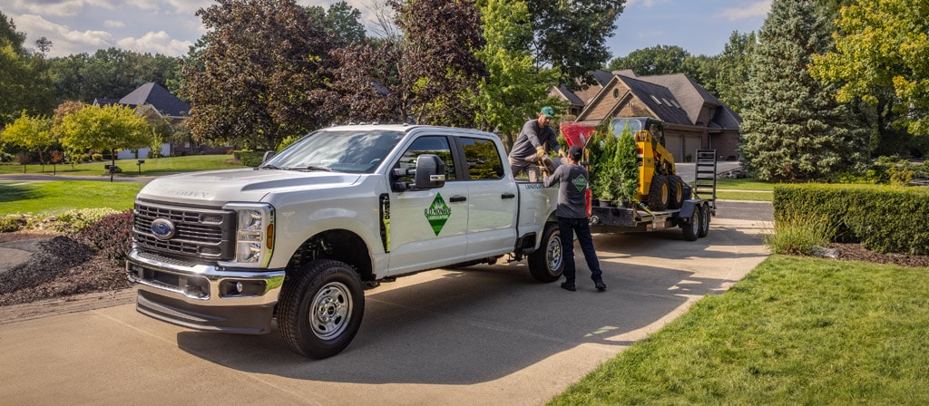 2026 Ford Super Duty® truck parked in a driveway towing a large trailer with equipment for landscaping