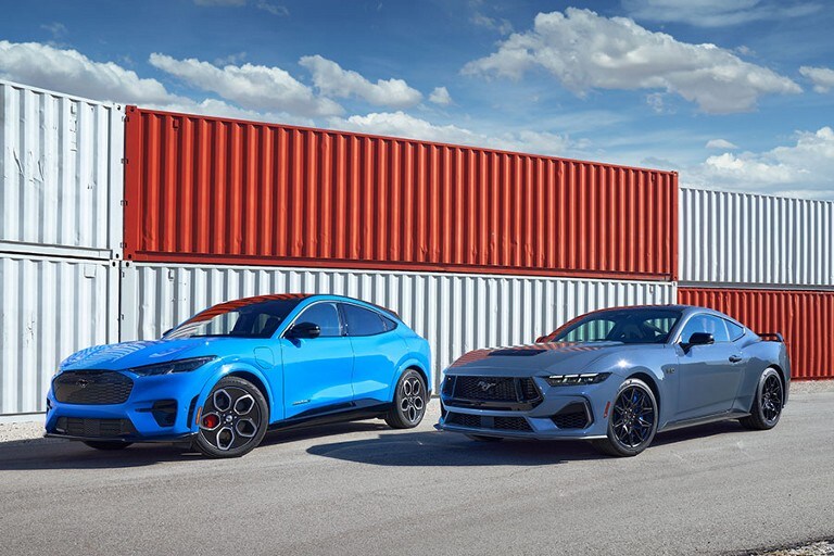 Two 2023 Ford Mustang Coups parked near shipping containers