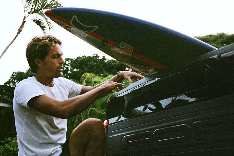 Kai Lenny fastening his surfboard in the bed of a Ford Super Duty® pickup