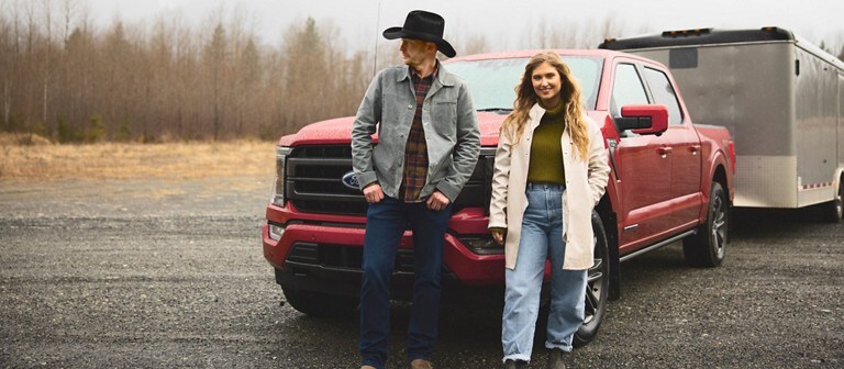 A couple poses behind a red 2021 Ford f 1 50