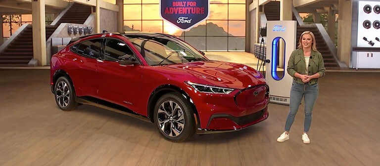 A woman stands next to a red 2021 Ford Mustang Mach e