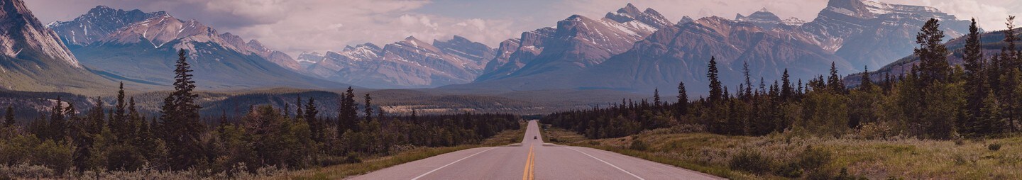 A two lane highway winds towards mountains in the distance