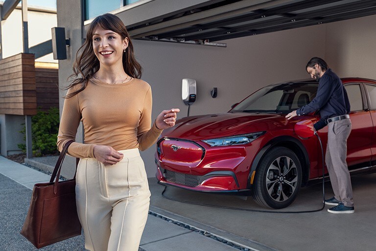 Man charges a red Mustang Mach-E in a garage with a Ford Connected Charge Station.