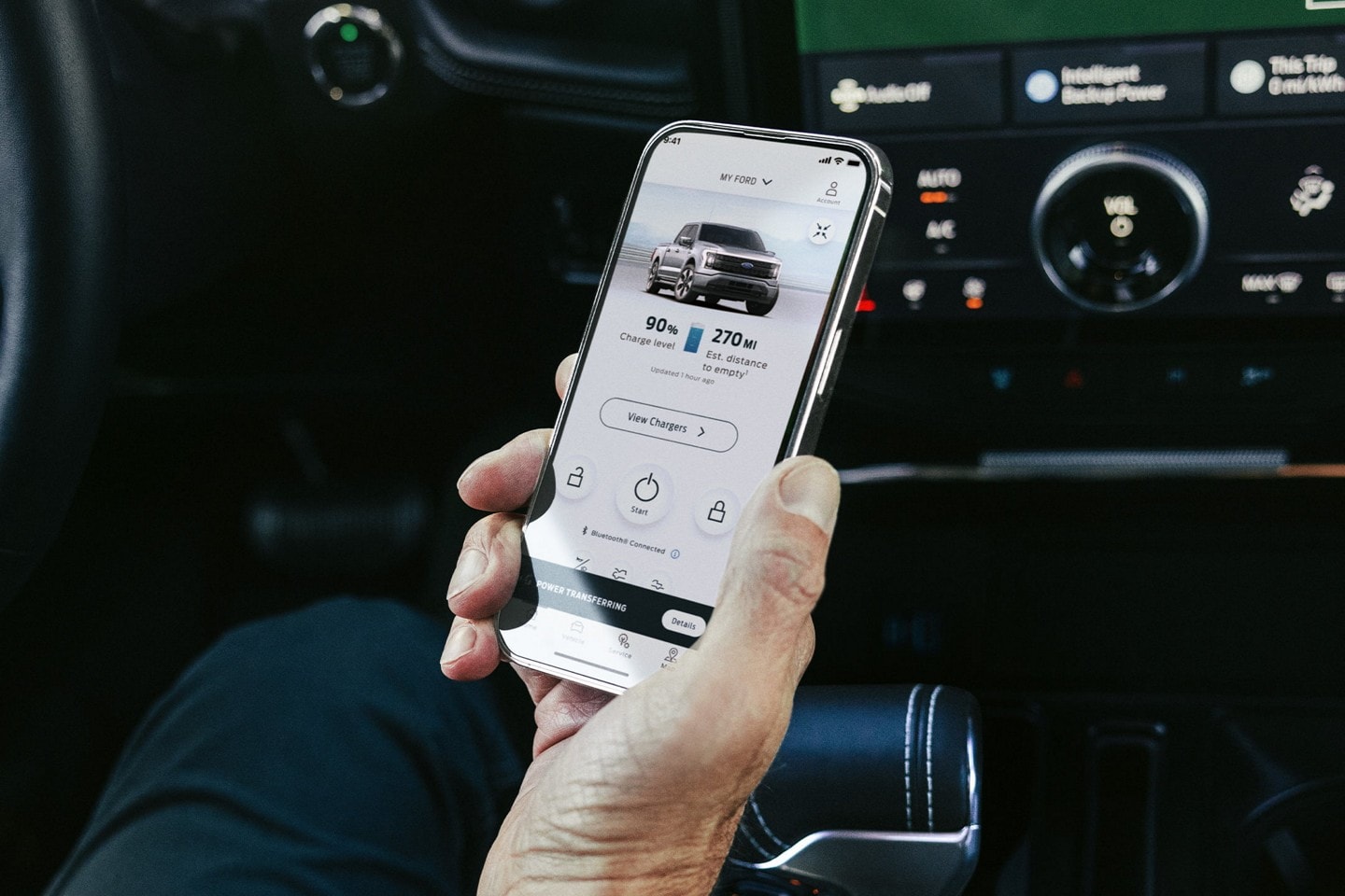 Person holding a smart phone displaying charging status of a vehicle.