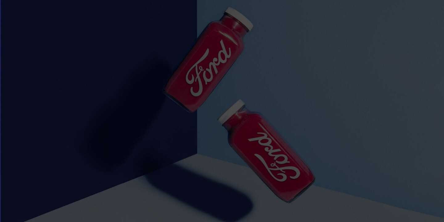Two juice bottles containing a red liquid with the Ford logo in white.