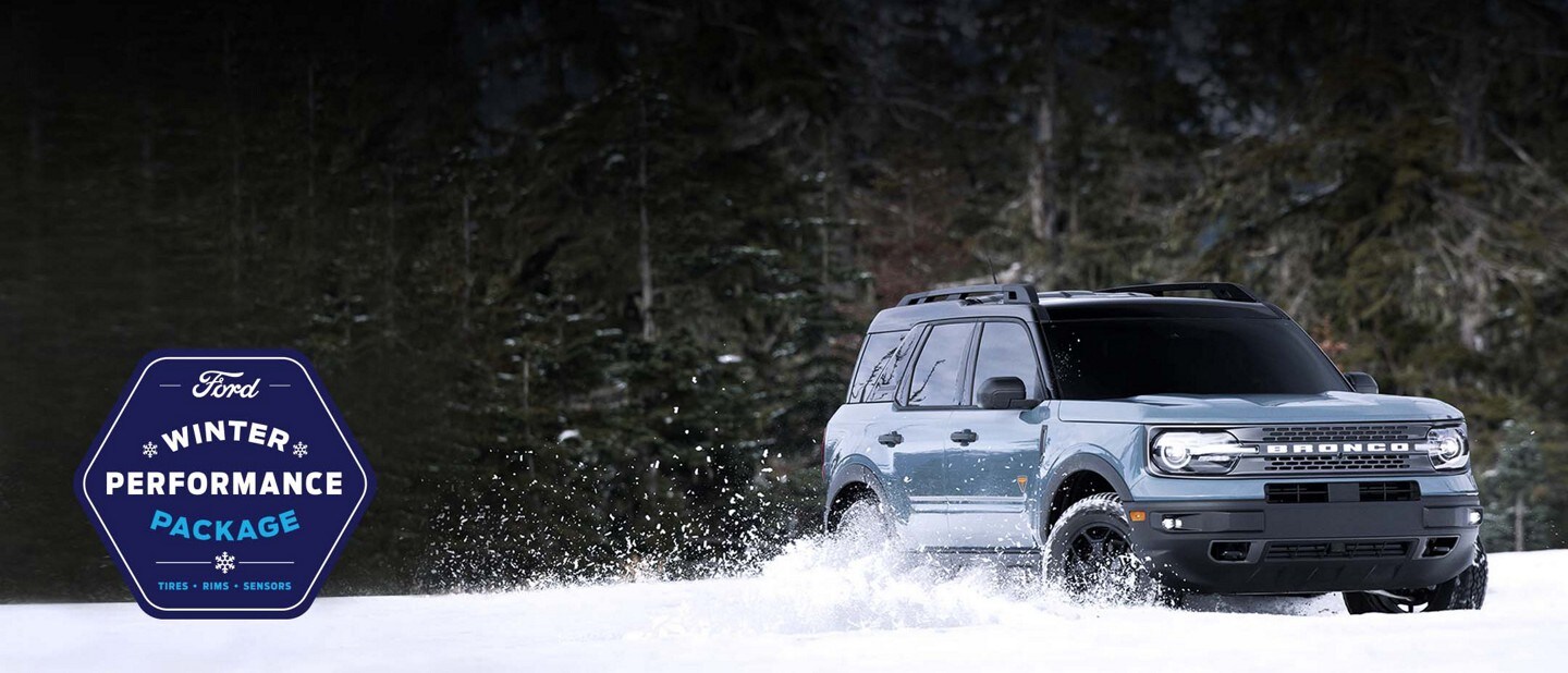 Ford Winter Performance Package. Tires, rims, sensors. A blue Ford Bronco drives through the snow.