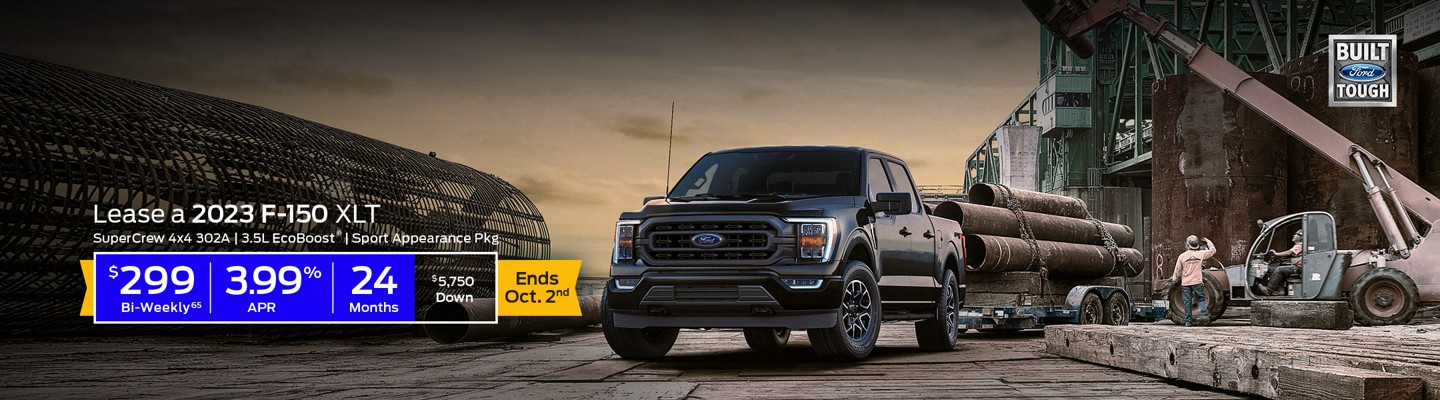Lease a 2023 F-150 XLT SuperCrew 4x4 302A/3.5L EcoBoost® V6/Sport Appearance Pkg, $299 Bi-Weekly65/3.99% APR/24 Months with $5,750 Down Payment. Ends Oct.2nd. A black 2023 Ford F-150 is seen hauling some heavy pipes on a towing trailor bed at a industrial site.