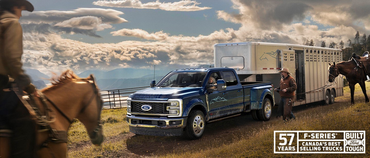 57 years. F-Series, Canada’s best selling trucks. Built Ford tough. A woman is driving a navy 2023 Ford Super Duty Truck beside of a man walking his horse in a farm setting.