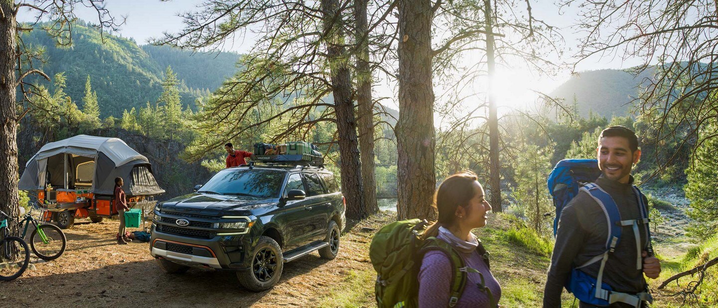 A Ford Expedition is parked at a busy camp site