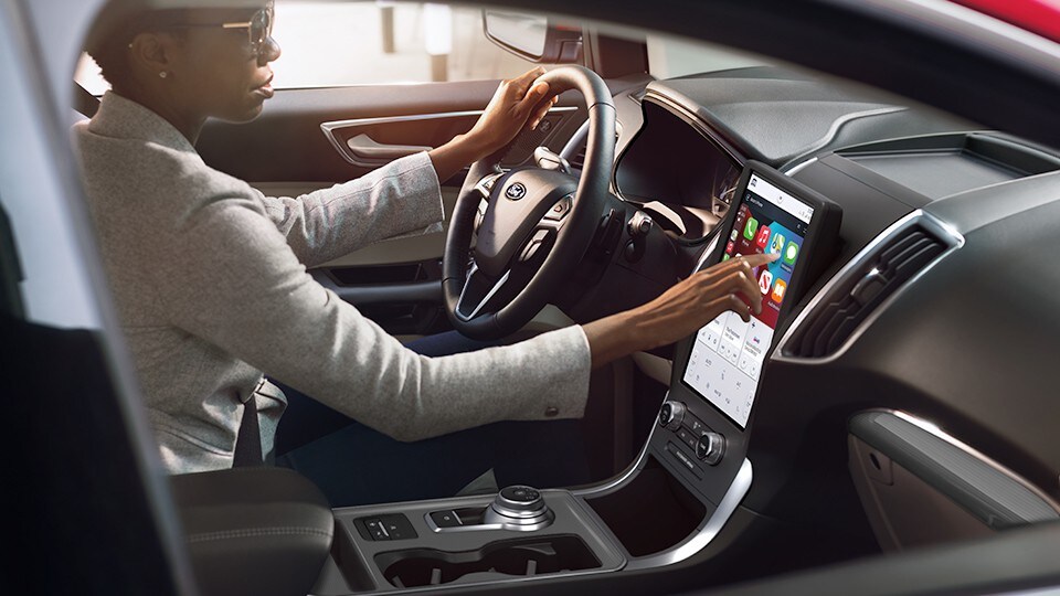 A woman operates the 12" touchscreen in a Ford vehicle.