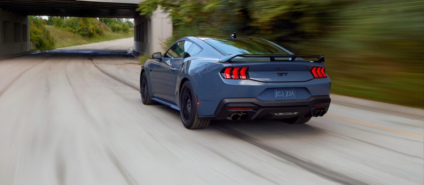 A blue 2025 Mustang GT driving on the highway. 