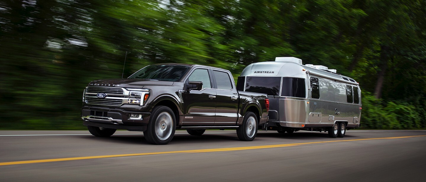 A 2024 Ford F-150® pickup in Agate Black pulling an Airstream Camper