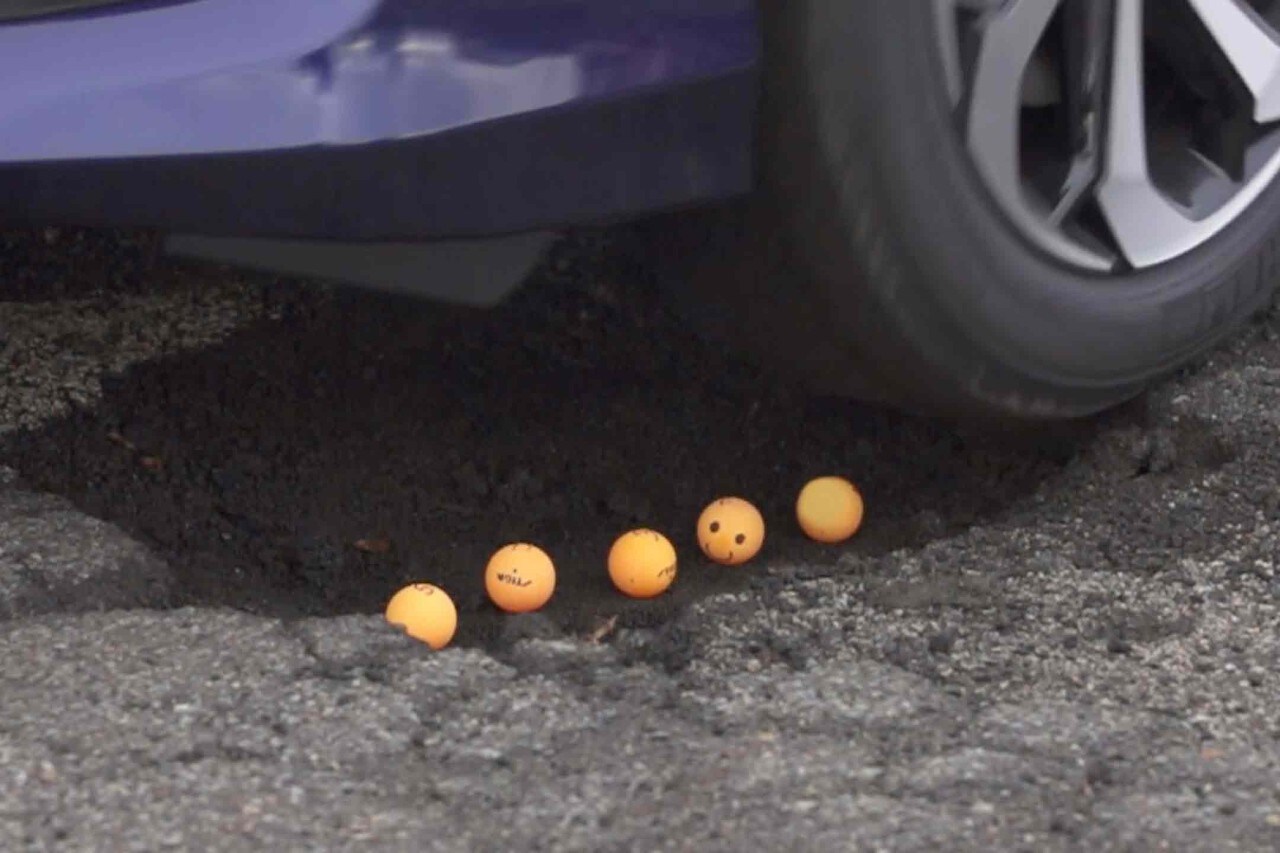 Car drives over large pothole