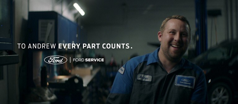 A smiling Ford technician standing in a garage