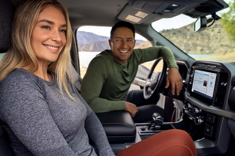 Two people sit inside a Ford vehicle