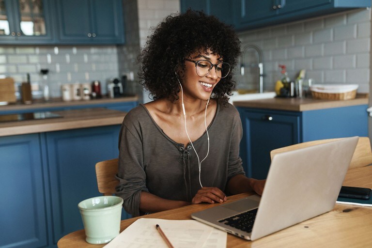 A person wearing headphones sits in front of a laptop