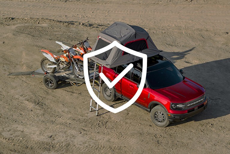 2021 Ford Ranger truck in Race Red parked on muddy ground fitted with a skyrise roof tent carrying two dirt bikes