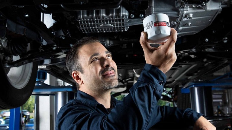 A Ford service technician replaces an oil filter