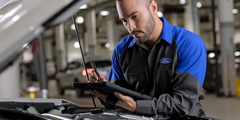 A Ford service technition consults a checklist