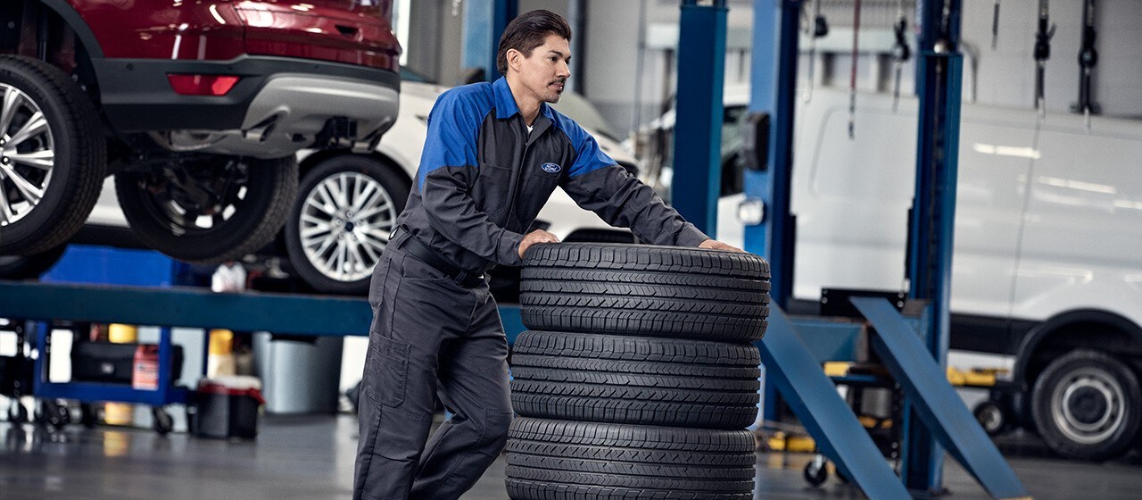 A Ford Service technician pushes a stack of tires
