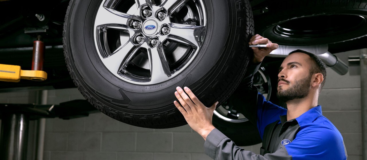 A technician examines a tire for wear
