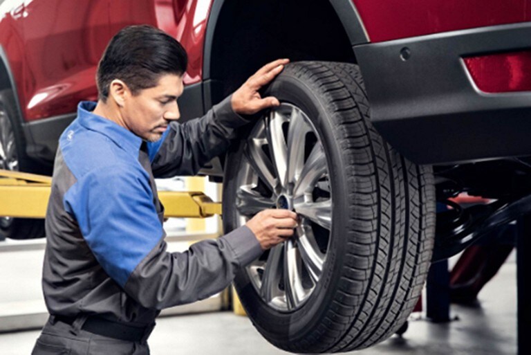 A Ford technician checking a vehicle’s tire
