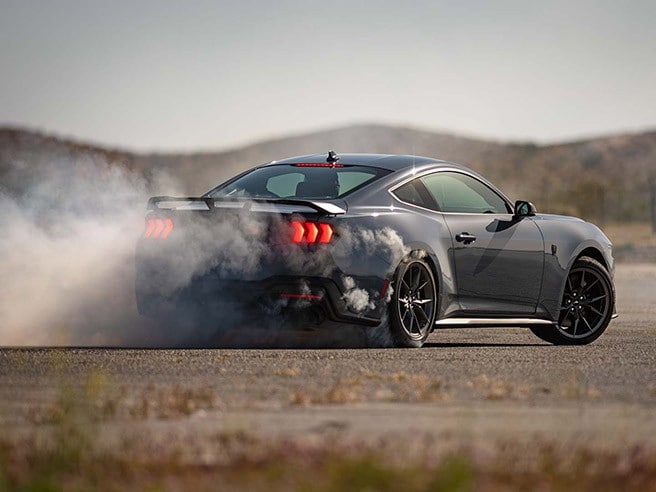 A Mustang® Dark Horse™ coupe smoking tires on desert pavement