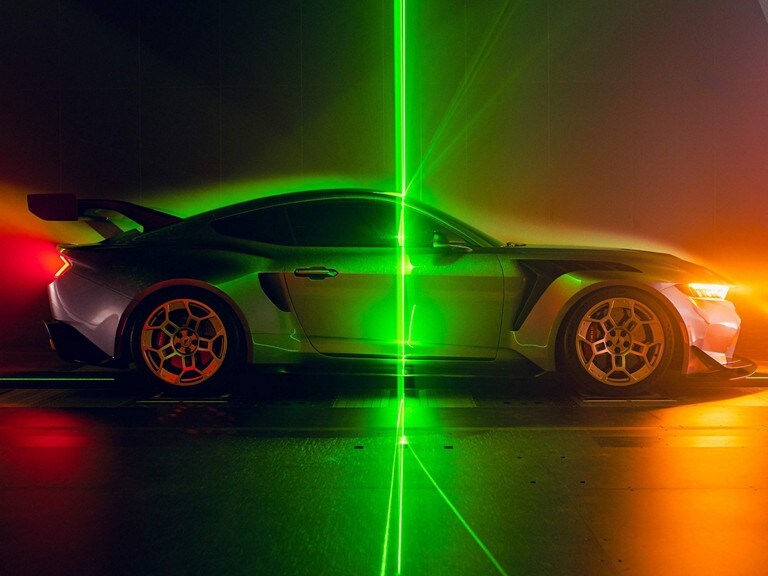 Side profile of a parked 2025 Mustang® GTD with a laser beam background.