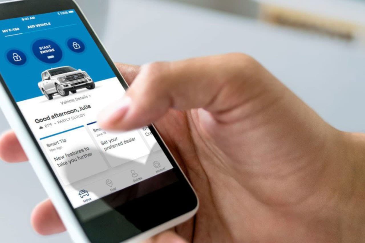 A hand holding a phone displaying FordPass