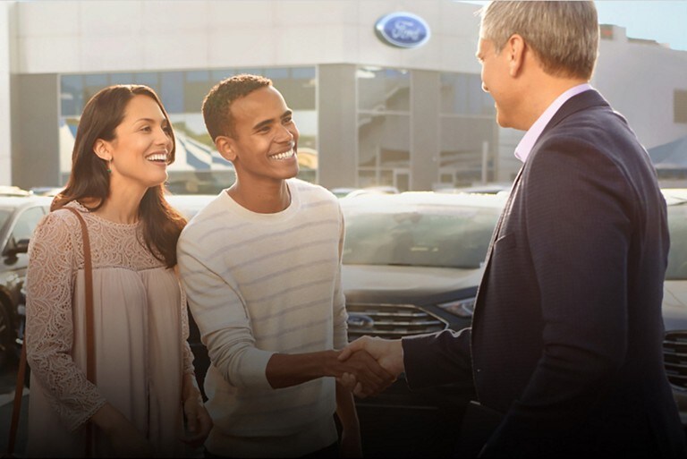 A Ford representative speaking to Ford customers at a dealership