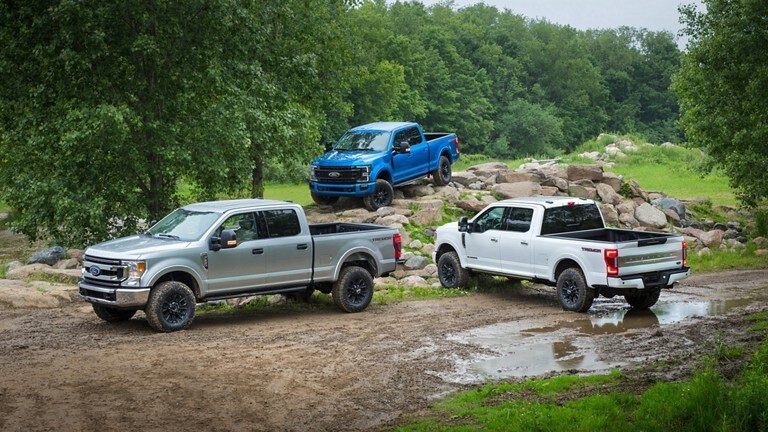 Three Ford Trucks around a mound of mud