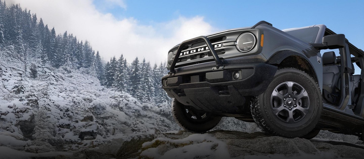 Front half of a 2025 Bronco with doors off parked on a snowy mountain.