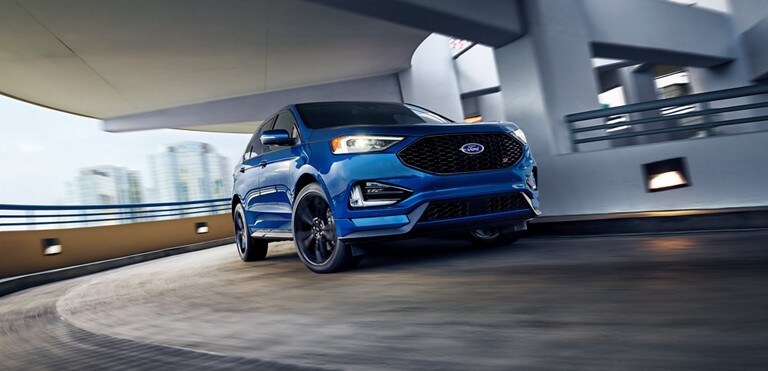 A blue Ford Edge on a spiral parking garage ramp.