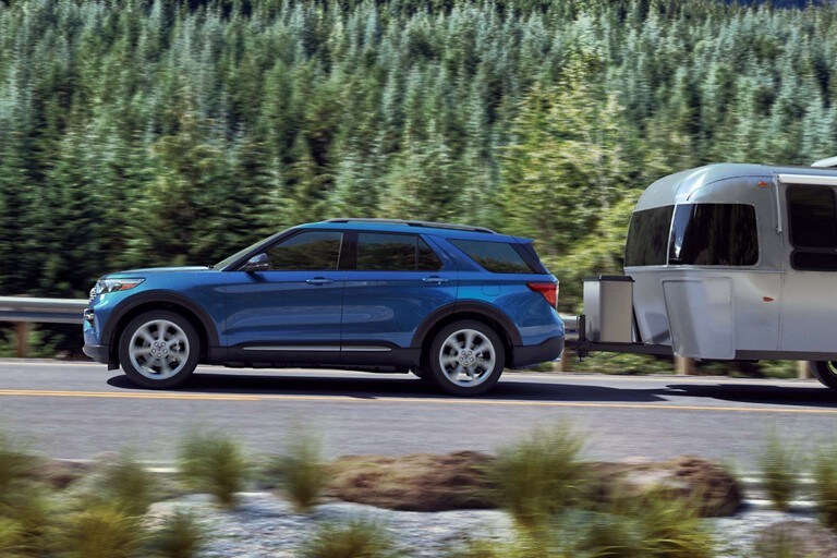 2020 Explorer Platinum Hybrid in Blue towing a trailer on the highway.