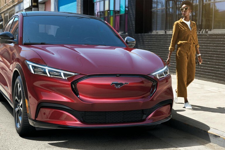 A woman standing next to a Mustang Mach-E in Rapid Red