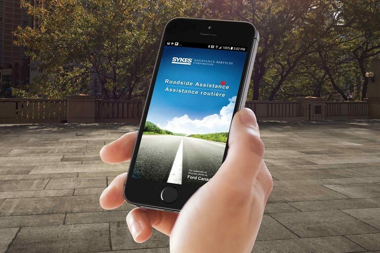 Hand holding mobile phone running the Roadside Assistance app