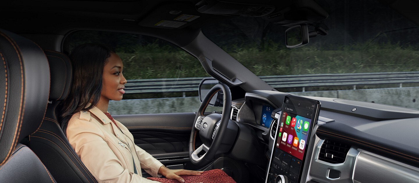 Interior view of a woman driving a vehicle hands-free on a highway
